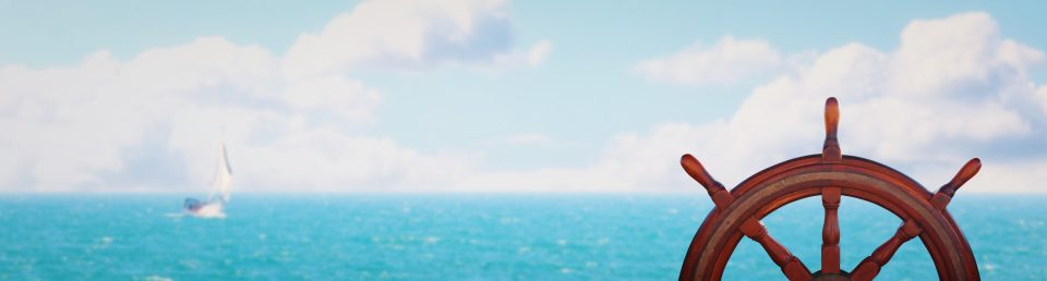 vintage nautical detail of a steering wheel of a ship in front of the sea. banner